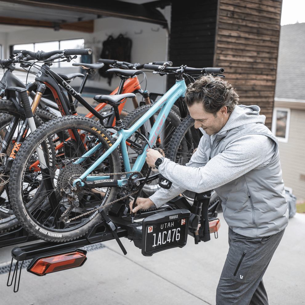 A man tilts the Thule Verse hitch bike rack with the 2 bike add-on.
