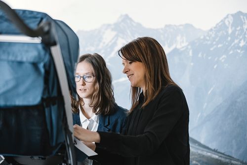 Duas pessoas estão avaliando os materiais de um carrinho para recém-nascidos Thule.