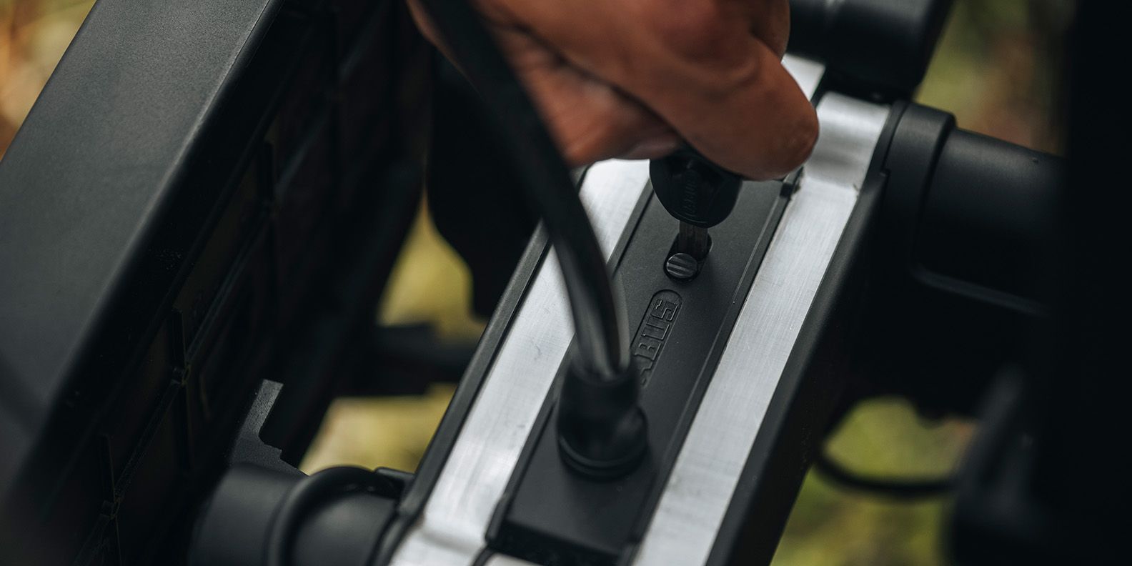 Primo piano di una mano che chiude Thule High Grade Bike Lock (venduto separatamente)