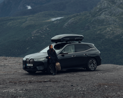 Woman leaning towards a car with a bag in her hand.