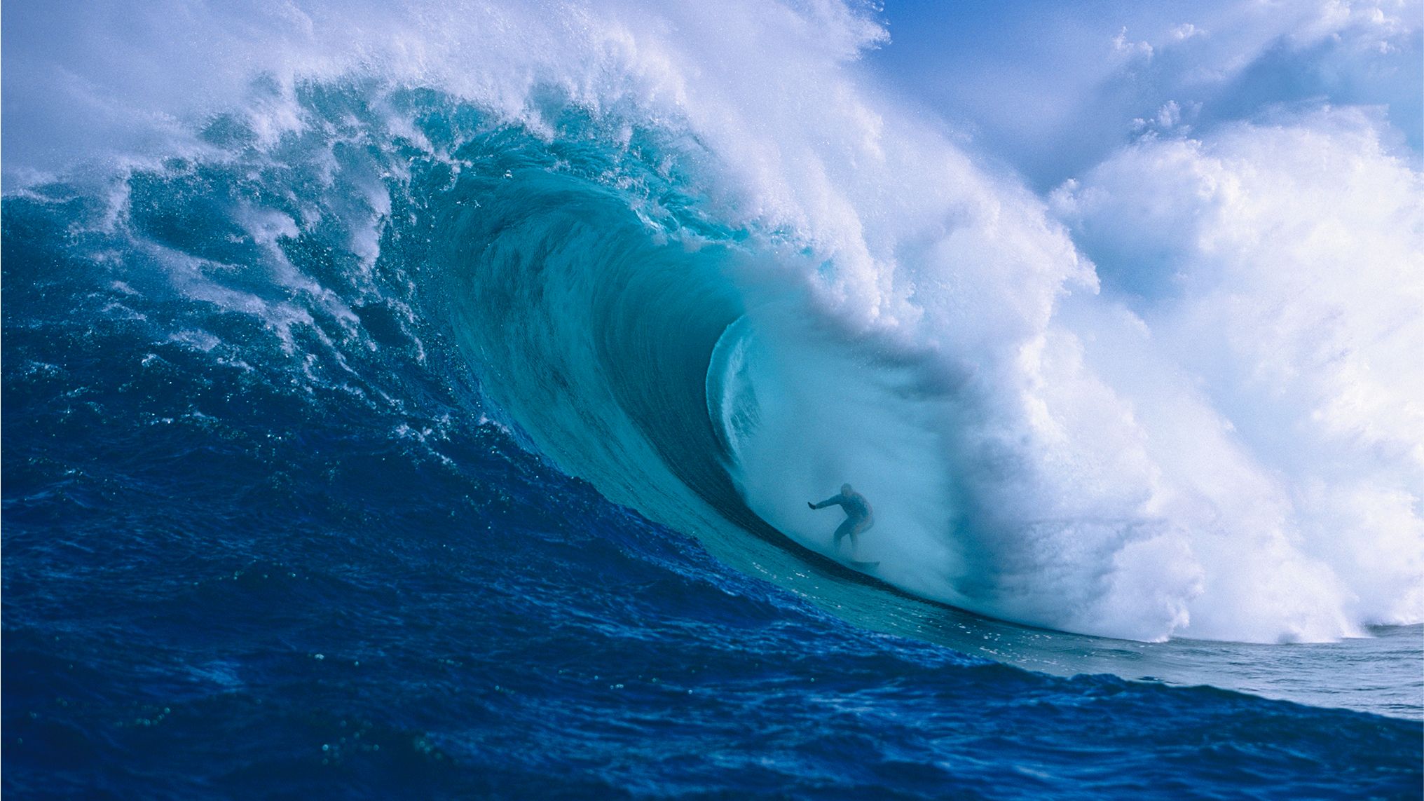 Una persona surfeando a través de una ola enorme.