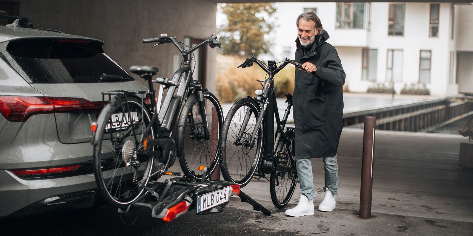 Un homme utilise la rampe de chargement pliable Thule Epos (vendue séparément) pour charger un lourd vélo électrique sur le porte-vélos Thule Epos